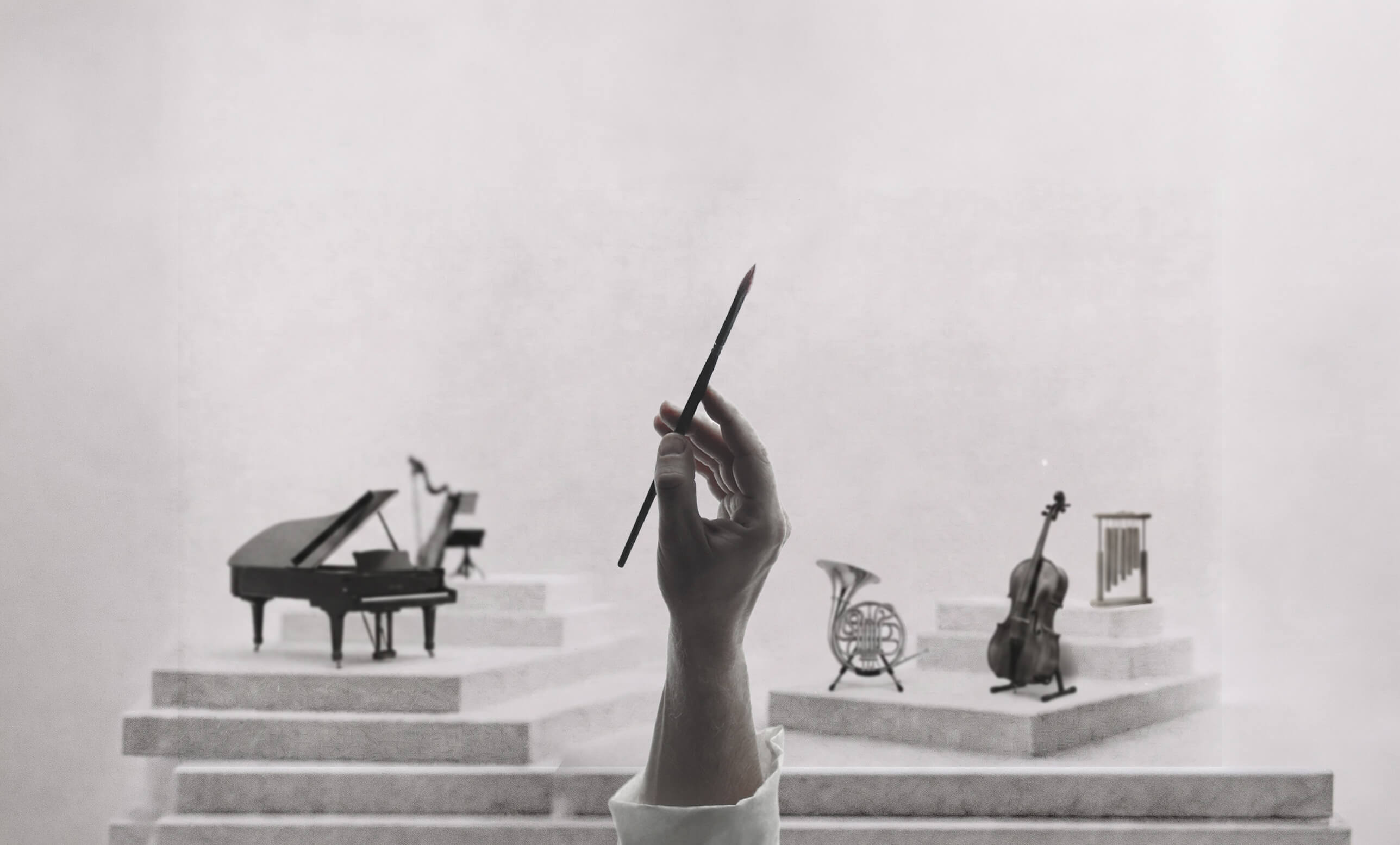 A hand holding a pencil raised like a conductor's baton, before a small orchestra of instruments